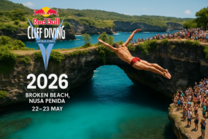 alt_text: Dua orang melompat dari tebing ke laut di Bali, memacu adrenalin dengan latar pemandangan indah.